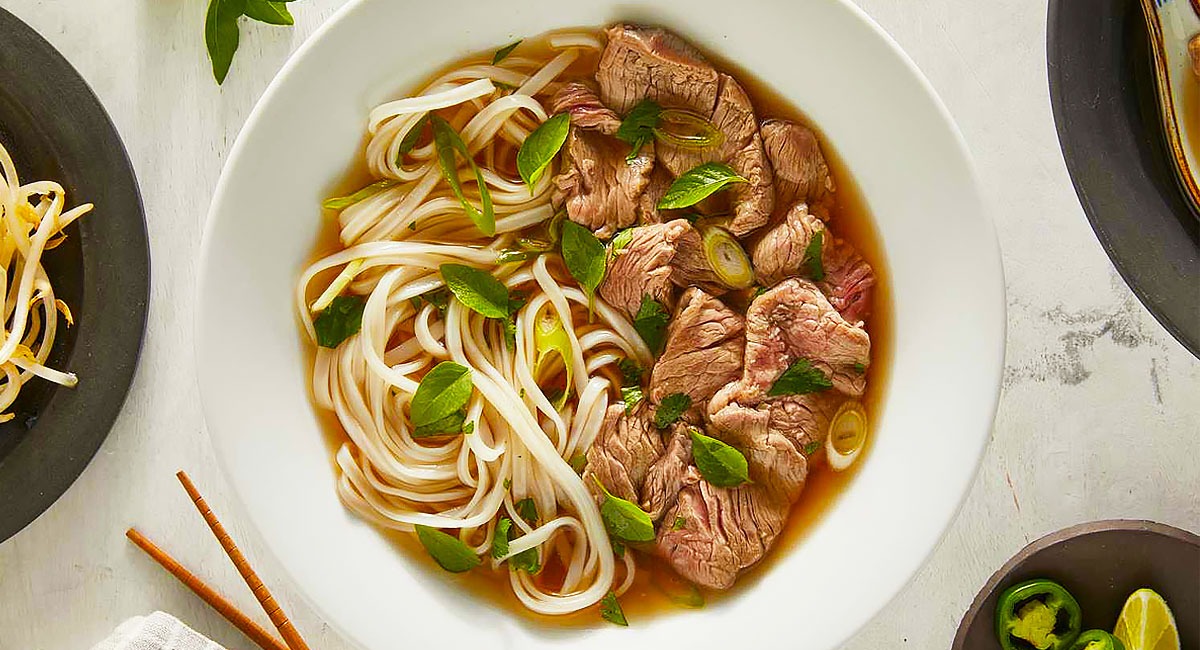 Bowl of Vietnamese Pho Soup with Fresh Herbs and Noodles