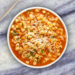 A bowl of steaming Pasta e Fagioli Soup with diced vegetables, beans, pasta, and a sprinkle of Parmesan cheese.