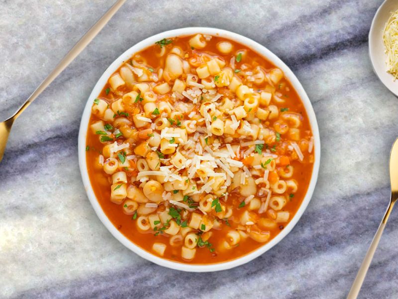 A bowl of steaming Pasta e Fagioli Soup with diced vegetables, beans, pasta, and a sprinkle of Parmesan cheese.
